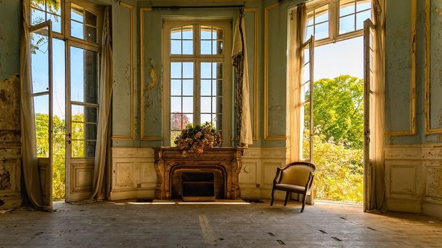 Leerer alter Salon mit Kamin und Sonnenlicht