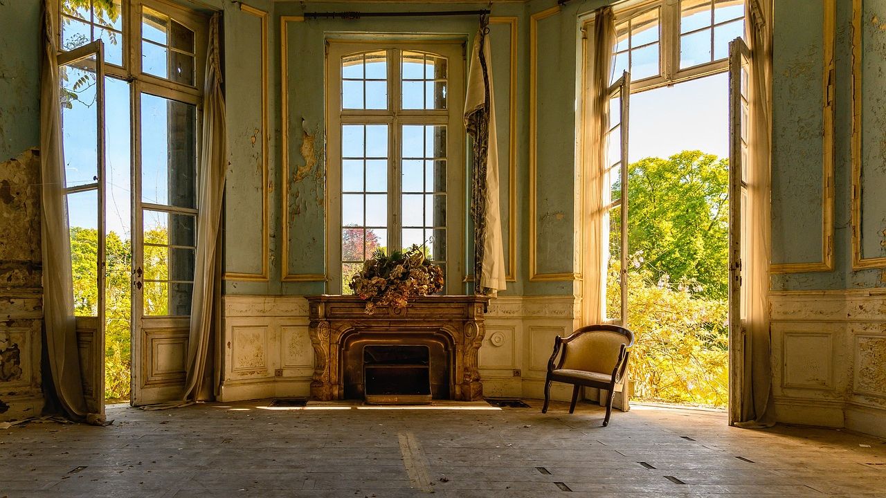 Leerer alter Salon mit Kamin und Sonnenlicht
