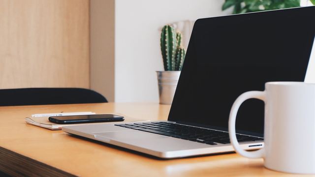 Laptop und Tasse auf einem Bürotisch