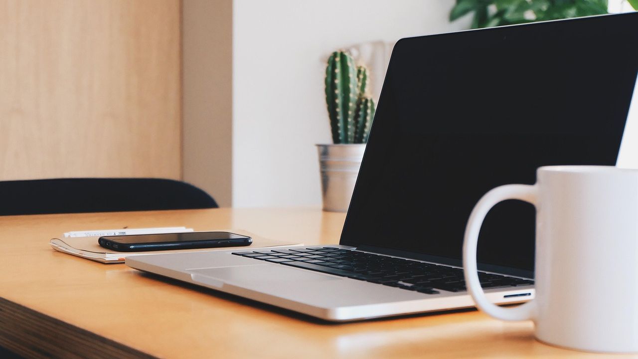 Laptop und Tasse auf einem Bürotisch