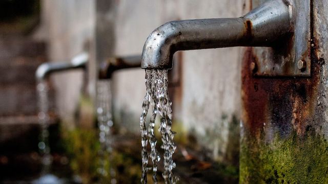 Wasser fließt aus einem alten Brunnenhahn